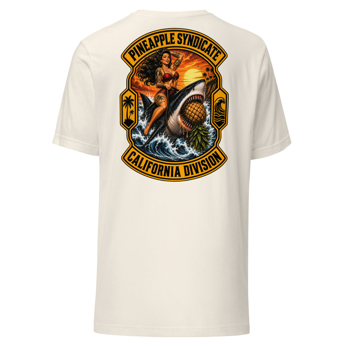 Pineapple Syndicate California Division tee featuring a tattooed pinup riding a great white shark through crashing waves with an upside-down pineapple, sunset coast, palm icons, and bold black-and-gold framing.