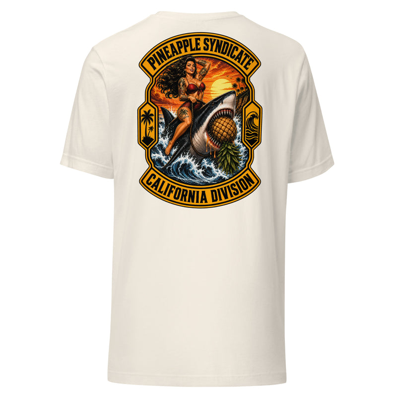 Pineapple Syndicate California Division tee featuring a tattooed pinup riding a great white shark through crashing waves with an upside-down pineapple, sunset coast, palm icons, and bold black-and-gold framing.