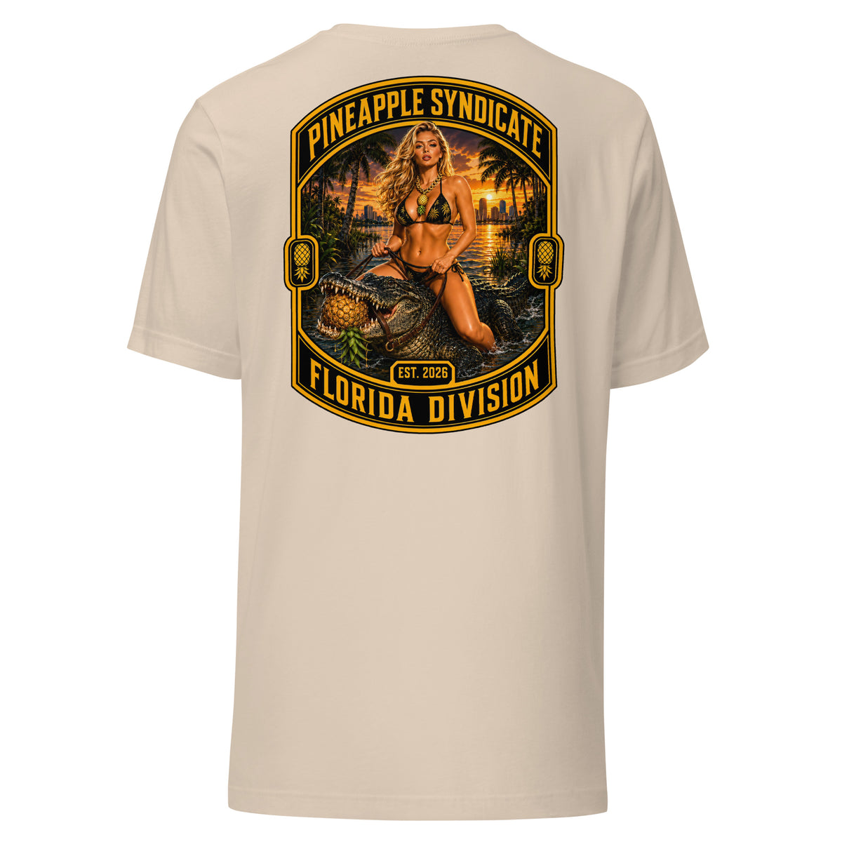 Pineapple Syndicate Florida Division tee featuring a blonde pinup riding an alligator through swamp water with an upside-down pineapple, sunset backdrop, and bold black-and-gold framing.
